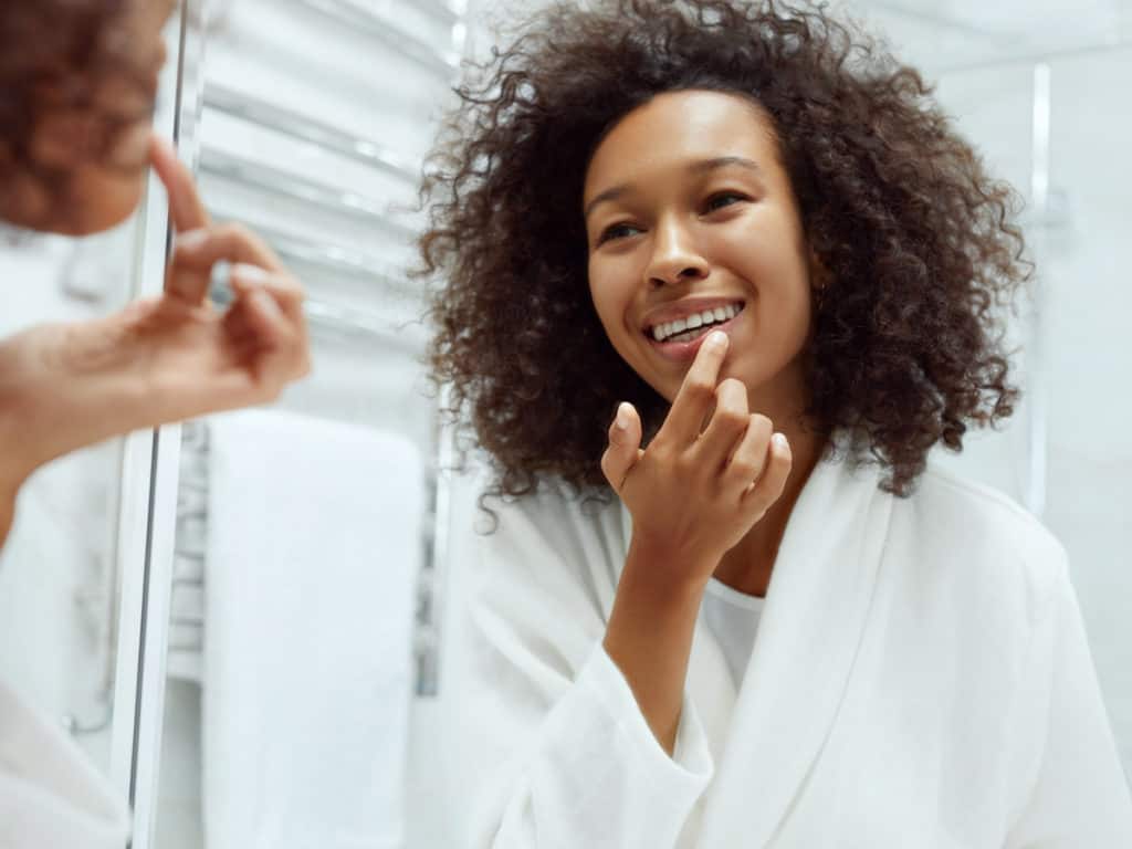 Woman with curly hair looking at herself in the mirror