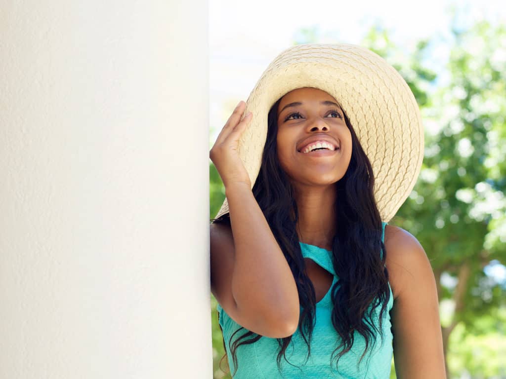 Young woman standing outside in a sun hat