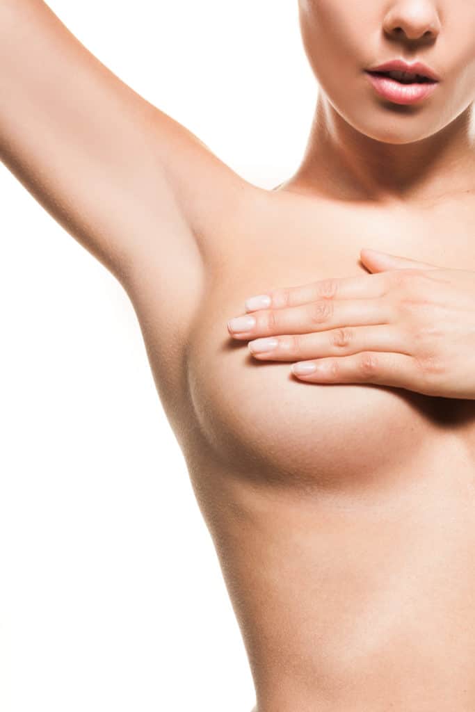 Close up of a naked woman holding her breast