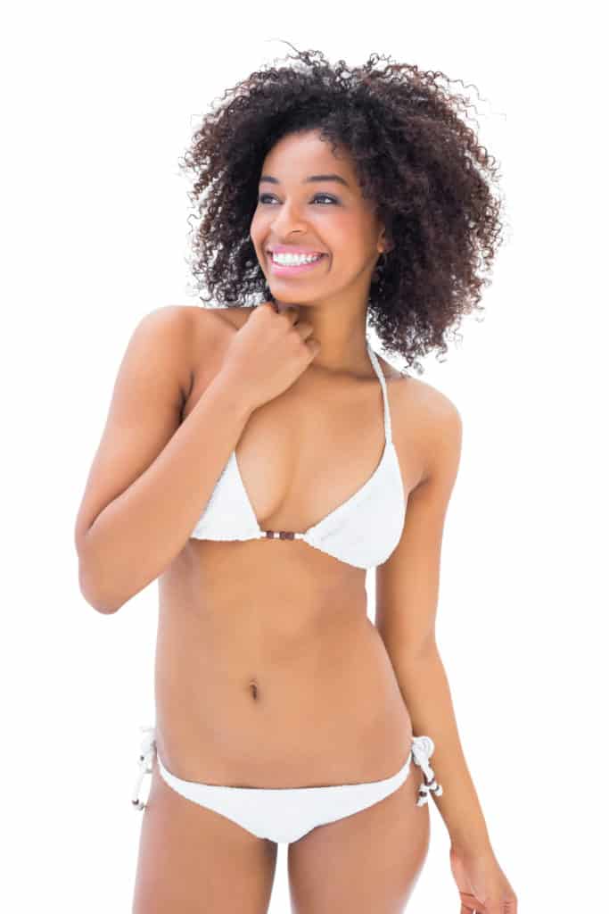 Fit girl in white bikini smiling and posing on white background