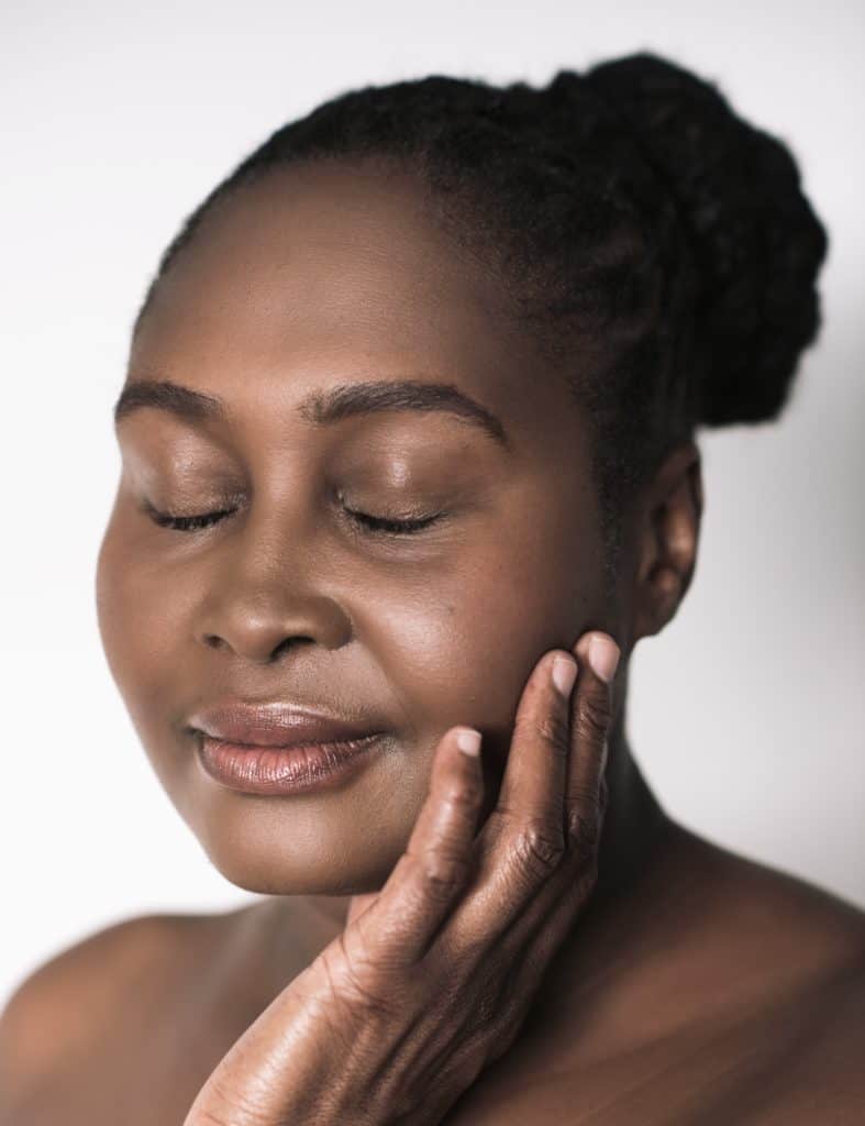 e African woman with perfect skin standing against a white background